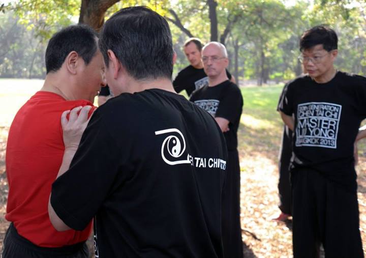 chen taichi teacher correcting student training at the park
