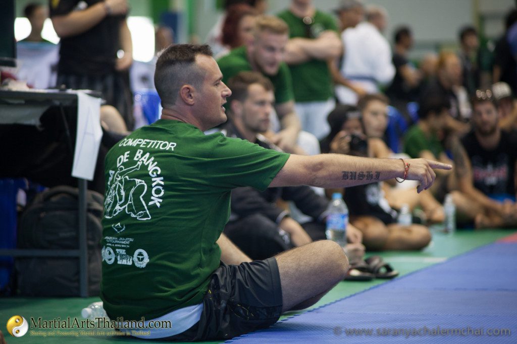 guy in green shirt sitting on floor watching a match