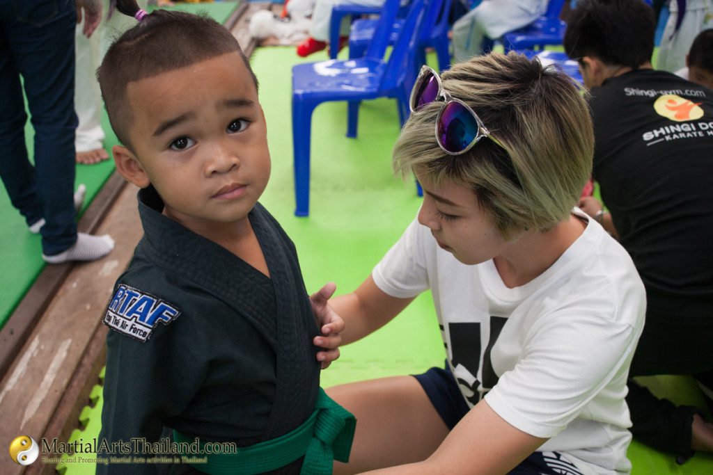 kid wearing black uniform getting ready by adult blond girl