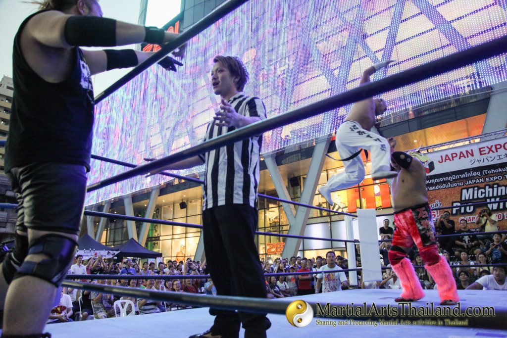 referee talking to fighter while another jumps illegally behind him at Pro-Wrestling Japan Expo 2016 Bangkok