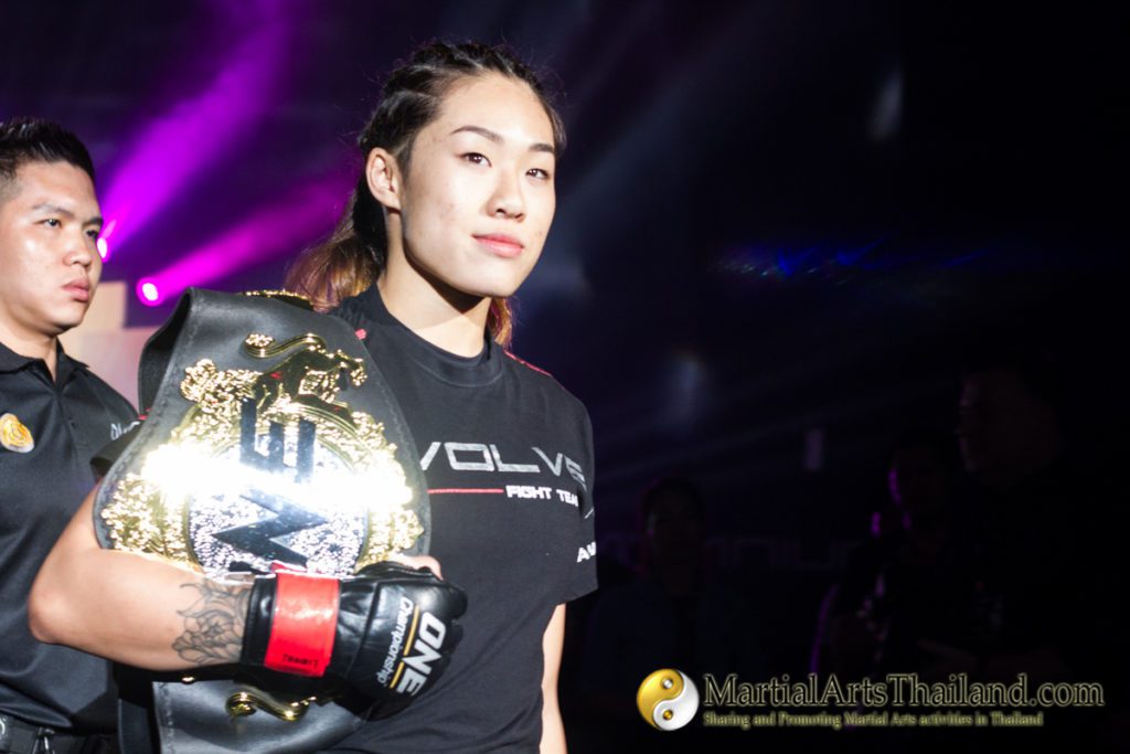 Angela Lee walking with her champion belt on her shoulder