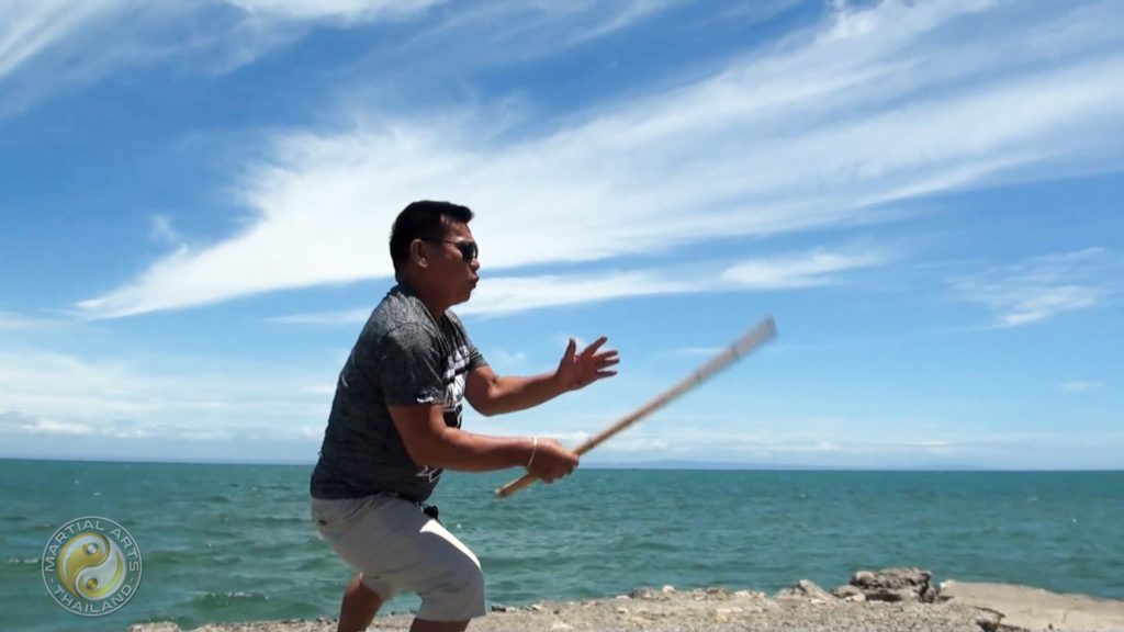 Jun Carin single stick training on a rock at sea shore