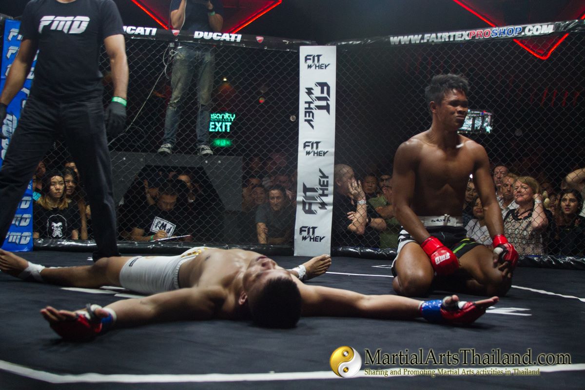 fighters resting on the ground inside the cage at FMD after the fight