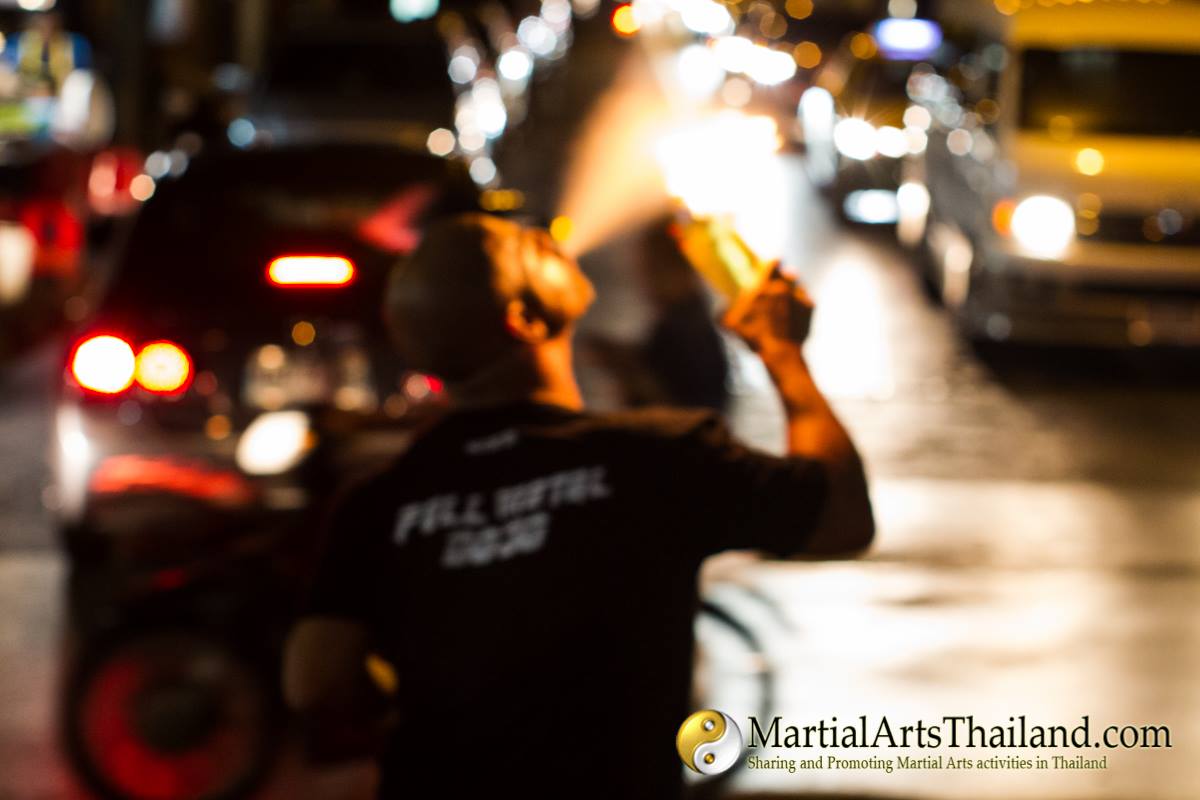 man spit fire with bangkok traffic in background
