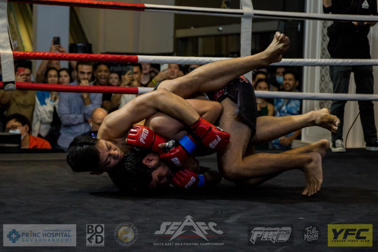 Simon Stracey attempting a rear naked choke on Suwattana Takanratti during their MMA match